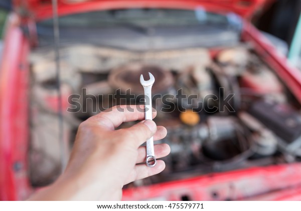 Wrench in hand on the\
background of cars