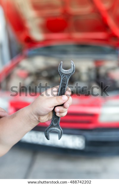 Wrench in hand on the\
background of cars
