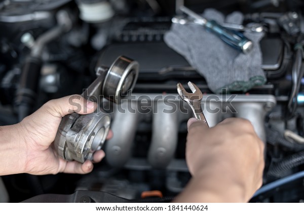 Wrench in the hand of a technician for take off Belt\
Tension Pulley old part car engine Replacement of spare parts in\
engine room