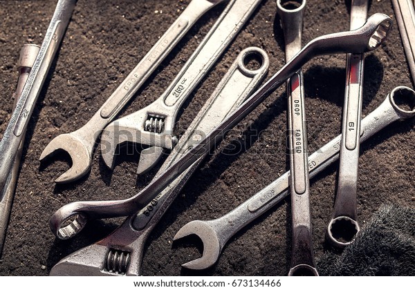 wrench, spanner, monkey wrench, screw\
wrench, diverse wrench tools on dirty cloth in\
garage