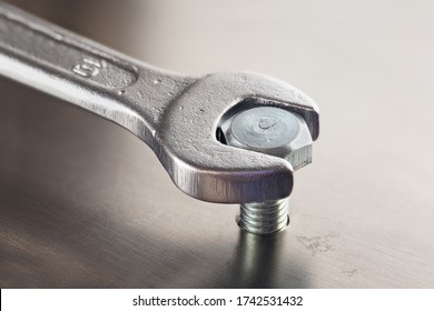 Wrench tightens  bolt in steel billet. Spanner, bolt, screw and nuts.