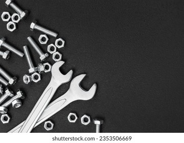 Wrenches with bolts and nuts on black background. Top view. Copyspace..