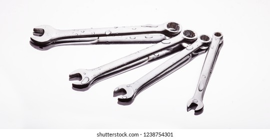Wrenches of different sizes on a light background in a stream of water.