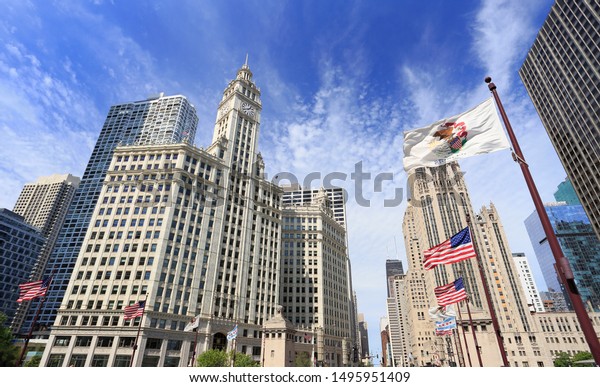 Wrigley Building and\
Tribune Tower on Michigan Avenue with Illinois flag on the\
foreground in Chicago,\
USA