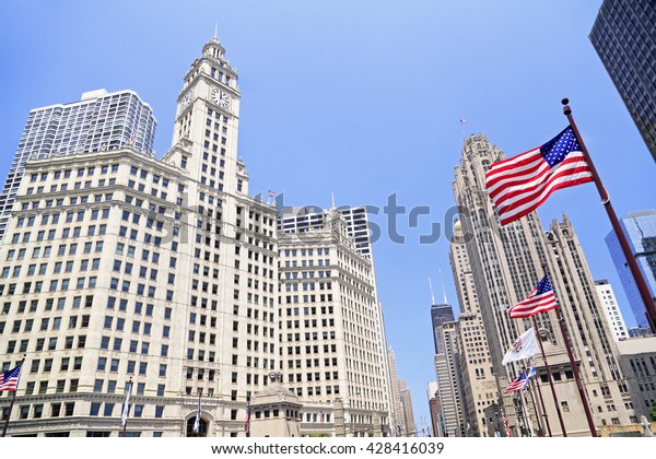 Wrigley Building and\
Tribune Tower on Michigan Avenue with American flag on the\
foreground in Chicago,\
USA