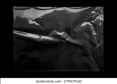 Wrinkle transparent shiny plastic wrap overlay on black background