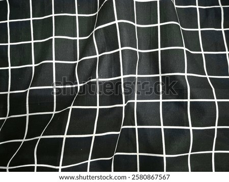 A wrinkled bed sheet with a checkered pattern, showcasing a cozy and textured look.