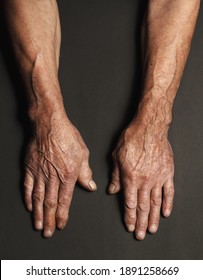 Wrinkled hands of an elderly man on a table close-up isolated on a black background. Top view.