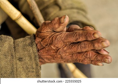 Wrinkled hands of an Indian holding a stick