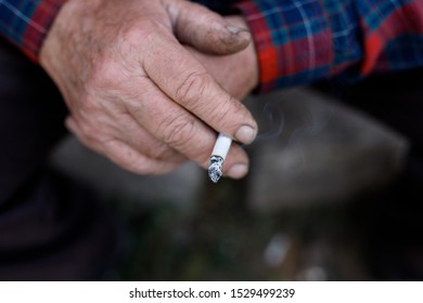 Wrinkled hands of old man with cigarette.