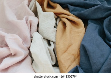 Wrinkled linen cloth folded napkins. Linen fabric texture. Light pink beige ivory mustard blue background. Image has shallow depth of field