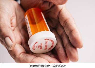 Wrinkled Old Lady Hands Holding A Bright Red Orange Prescription Medication Pill Bottle.