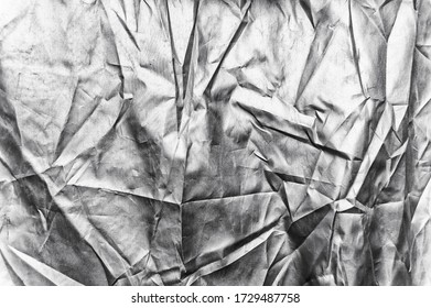 Wrinkled Silver Metallic Fabric. Folded Fabric Which Looks Like Foil. Metallic Cloth. Light Sliver Metallic. Warped Crumpled Fabric. Glossy Cloth Texture