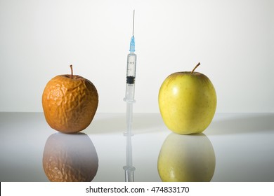 Wrinkled and smooth apples and the syringe between them