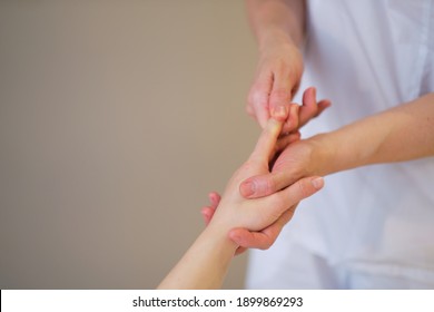 Wrist Massage. Massage Therapist Puts Pressure On A Sensitive Point On A Woman's Hand. Physiotherapist Massaging Her Patients Hand In Medical Office