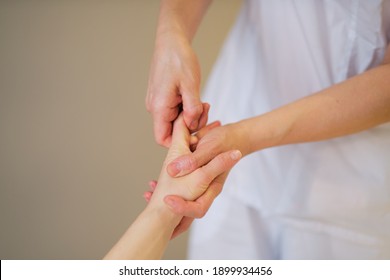 Wrist Massage. Massage Therapist Puts Pressure On A Sensitive Point On A Woman's Hand. Physiotherapist Massaging Her Patients Hand In Medical Office