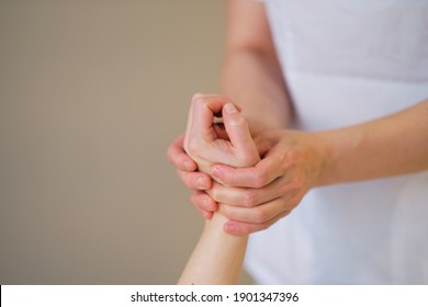 Wrist Massage. Massage Therapist Puts Pressure On A Sensitive Point On A Woman's Hand. Physiotherapist Massaging Her Patients Hand In Medical Office