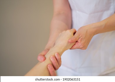 Wrist Massage. Massage Therapist Puts Pressure On A Sensitive Point On A Woman's Hand. Physiotherapist Massaging Her Patients Hand In Medical Office