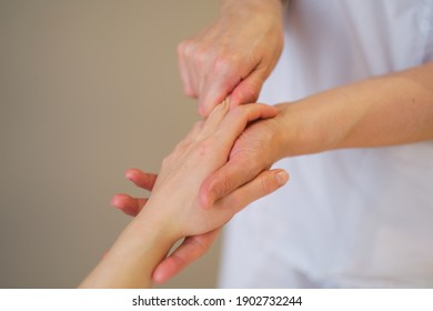 Wrist Massage. Massage Therapist Puts Pressure On A Sensitive Point On A Woman's Hand. Physiotherapist Massaging Her Patients Hand In Medical Office