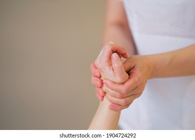 Wrist Massage. Massage Therapist Puts Pressure On A Sensitive Point On A Woman's Hand. Physiotherapist Massaging Her Patients Hand In Medical Office