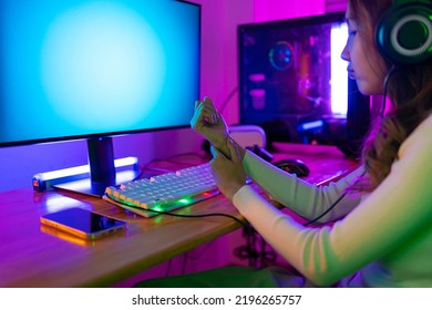 Wrist Pain Concept. Gamer And E-Sport Online Of Asian Woman Playing Online Computer Video Game With Lighting Effect, Broadcast Streaming Live At Home. Her Use Her Wrist For A Long Time.