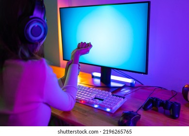 Wrist Pain Concept. Gamer And E-Sport Online Of Asian Woman Playing Online Computer Video Game With Lighting Effect, Broadcast Streaming Live At Home. Her Use Her Wrist For A Long Time.