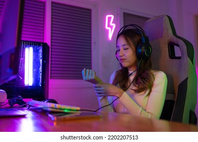 Wrist Pain Concept. Gamer And E-Sport Online Of Asian Woman Playing Online Computer Video Game With Lighting Effect, Broadcast Streaming Live At Home. Her Use Her Wrist For A Long Time.