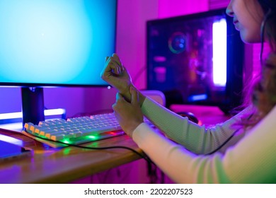 Wrist Pain Concept. Gamer And E-Sport Online Of Asian Woman Playing Online Computer Video Game With Lighting Effect, Broadcast Streaming Live At Home. Her Use Her Wrist For A Long Time.