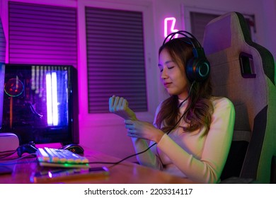 Wrist Pain Concept. Gamer And E-Sport Online Of Asian Woman Playing Online Computer Video Game With Lighting Effect, Broadcast Streaming Live At Home. Her Use Her Wrist For A Long Time.