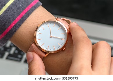 Wrist watch on girl's hand in front of a laptop computer