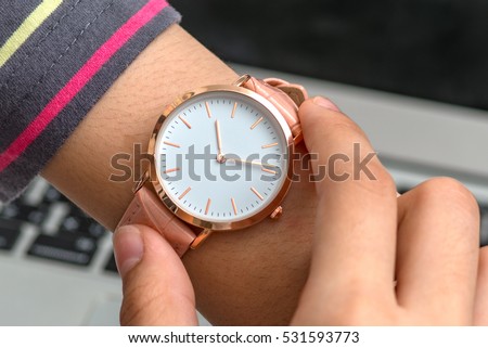 Wrist watch on girl's hand in front of a laptop computer