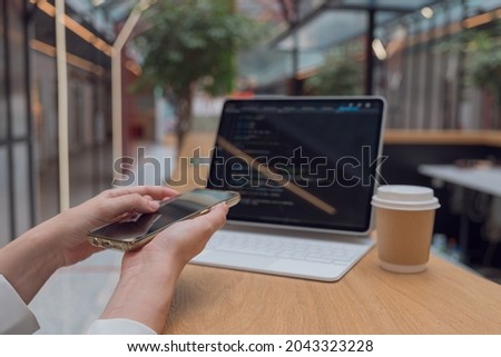 Write code or learn new programming languages. Pumping skills, online training. Cross-platform applications, a user in front of a laptop with a smartphone in his hands
