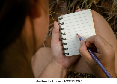 Write a feeling in a small notebook with a purple pencil.