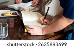 Writer taking notes in a notebook during a lively book club meeting, surrounded by cookies and refreshing glasses of water on the table