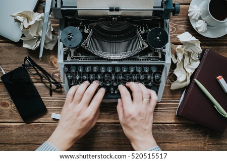 Writer typing with retro writing machine. View from above.