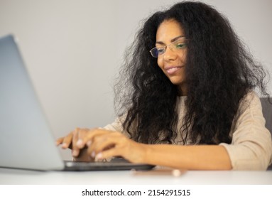 Writer Typing Text On Computer. Cheerful Black Woman Working On Modern Laptop At Home. Freelancer Person Doing Distant Work Online With Smile