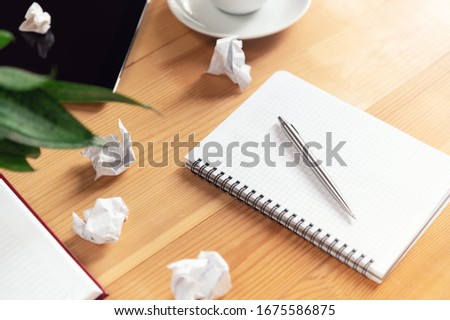 Writer workplace with notepad and pen. Crumpled papers, clear sheet in notebook on wooden table. Business planning and brainstorming. Creation process and authorship concept