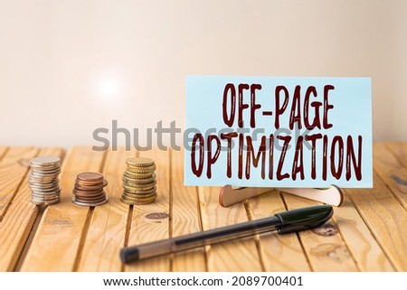 Writing displaying text Off Page Optimization. Word Written on Website External Process Promotional Method Ranking Empty Piece Of Paper On Holder Beside Stockpile Coins Over Desk With Pen.