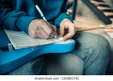 Writing down composition. Professional young musician writing composition in special album before daily repetition