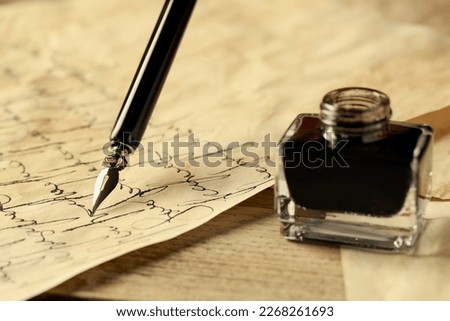 Writing with fountain pen on vintage parchment near inkwell at wooden table, closeup