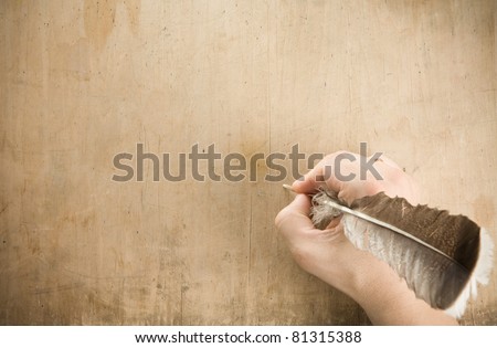 writing hand with pen feather at old wood background texture