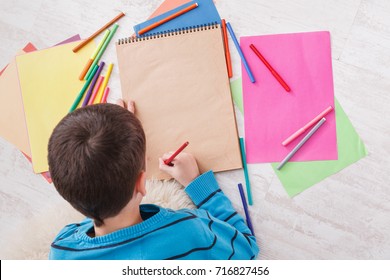 Writing letter to santa. Cute boy makes wish list of presents for christmas. Drawing picture. Prepare for winter holidays, top view of child on floor