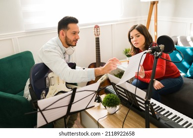 Writing The Lyrics Of A Song. Attractive Woman And Man Composing A New Song On A Music Sheet While Playing Instruments