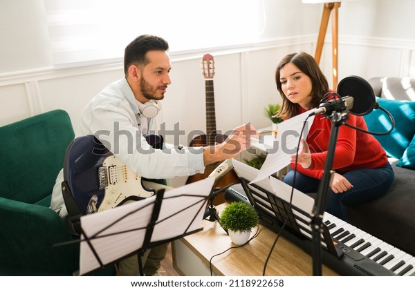 Writing the\
lyrics of a song. Attractive woman and man composing a new song on\
a music sheet while playing\
instruments