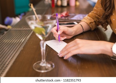 Writing Number. Young Girl Sitting At The Bar Counter And Writing Her Phone Number On The Piece Of Paper