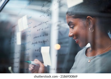 Writing, planning strategy and brainstorming ideas on a glass wall in a modern design office. Young business woman thinking and drawing up a plan for success on a transparent board in the boardroom - Powered by Shutterstock