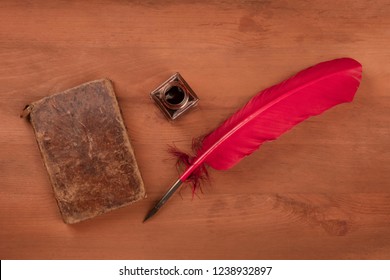 Writing Poetry. A Photo Of A Red Quill With And Ink Well And An Old Book, Shot From The Top On A Dark Wooden Table With Copy Space