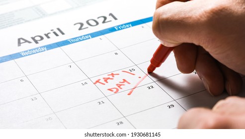Writing tax day on 2021 April 15 calendar with red marker. Deadline for 1040 form return.