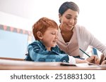 Writing, teacher and child in classroom for help in student growth, child development and advice for education. Learning, woman and boy at desk with exam notes, support and study at elementary school