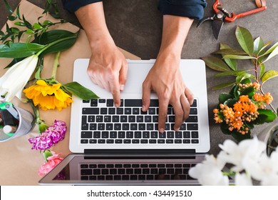 Writing and working on a laptop with flowers on the counter